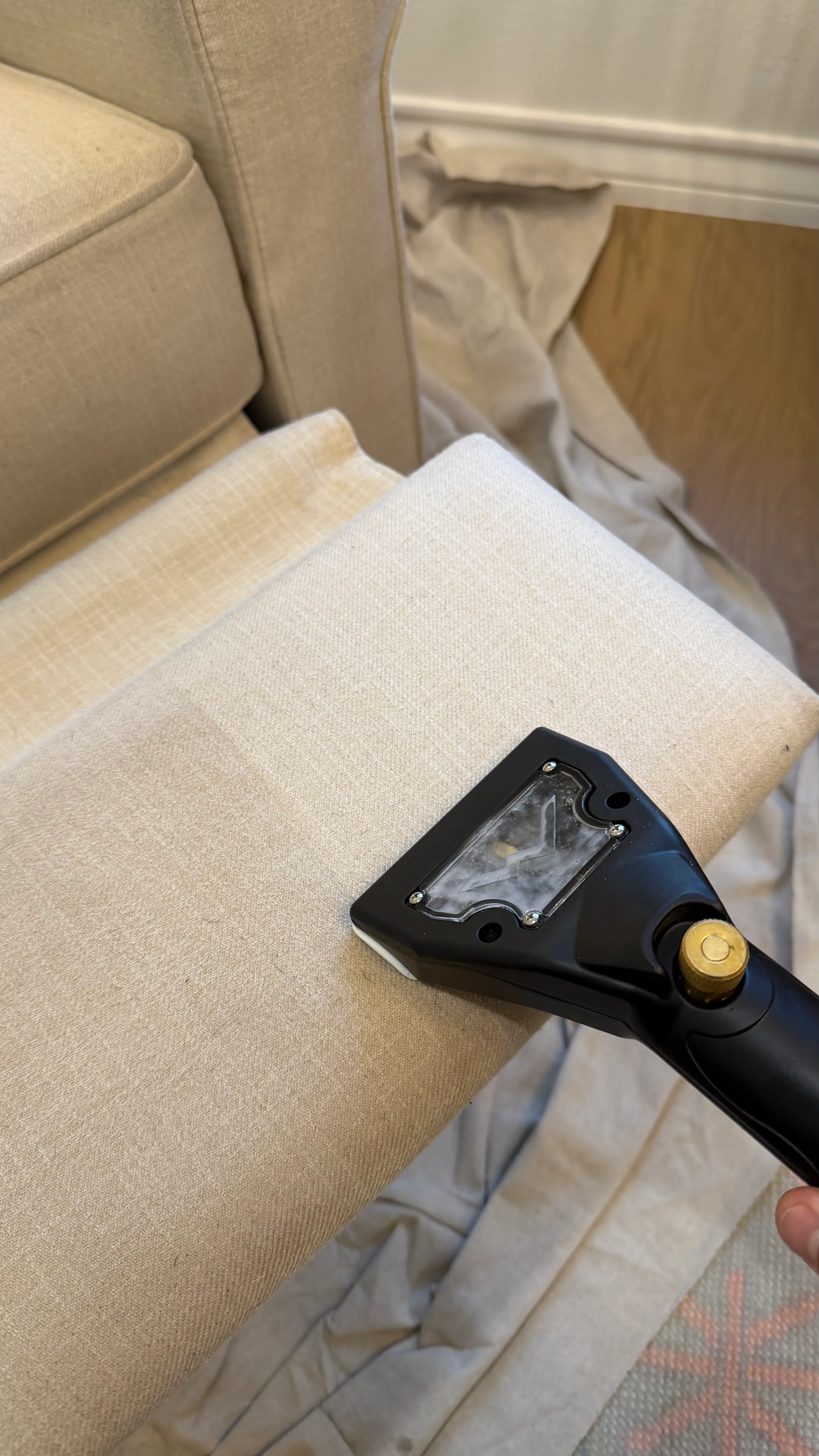 Upholstery cleaning in progress in Bowie, TX — hand tool extracting soil from a light fabric sofa